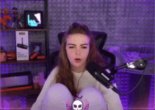 a girl sitting in front of a shure microphone