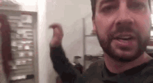 a man with a beard is standing in front of a closet in a room .