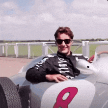 a man sitting in a race car with the number 8 on the side