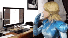 a woman in a superhero costume is looking at a computer monitor