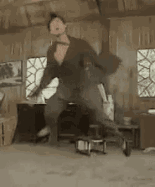 a man is dancing in a room with a chair and a table .