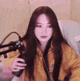a woman is sitting in front of a microphone while wearing headphones and a yellow jacket .