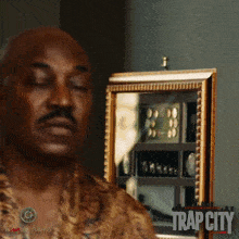 a man with his eyes closed stands in front of a mirror with trap city written on it