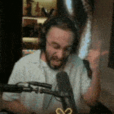 a man wearing headphones and glasses is sitting in front of a microphone and making a funny face .