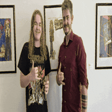 a man wearing an evangelion shirt stands next to a man in a red shirt