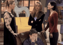 three women stand around a man covering his face in front of a poster that says matin
