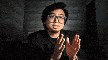 a man wearing glasses and a black shirt is giving a square of applause