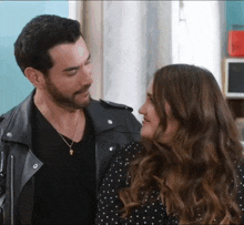 a man in a leather jacket and a woman in a polka dot dress look at each other