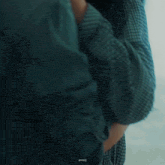 a man and a woman are kissing in front of a window . the woman is wearing a plaid shirt .