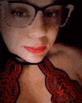 a woman wearing glasses and red lipstick is looking at the camera .