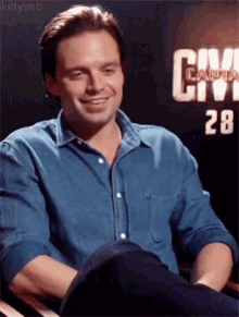 a man in a blue shirt is sitting in front of a sign that says civil war .