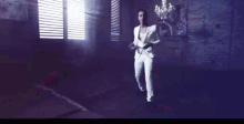 a man in a white jacket is pointing at the camera in a dark room .