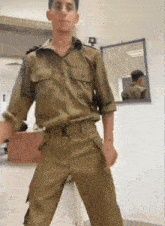 a young man in a military uniform is standing in front of a mirror .
