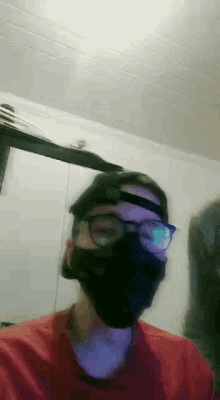a man wearing a mask , glasses and a hat is standing in a room .