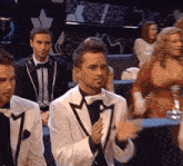 a group of men in tuxedos are sitting in a room