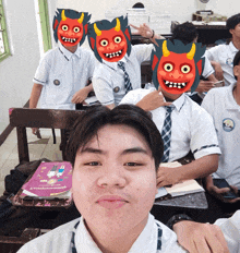 a boy in a classroom wearing a mask with a devil face