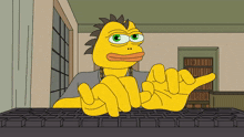 a yellow cartoon character is sitting at a keyboard and making a thumbs up sign