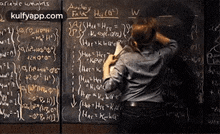 a man is standing in front of a blackboard filled with math problems