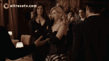 a group of people standing in a room with eltrecetv.com on the bottom right