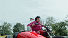a man is riding a red motorcycle on a road with trees in the background