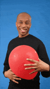 a man in a black shirt is holding a red balloon in his hand