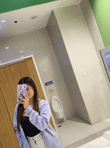 a woman is taking a picture of herself in a public bathroom