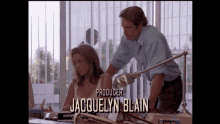 a man and a woman sitting at a desk with the producer jacquelyn blain