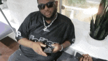 a man wearing sunglasses and a black shirt with the letter r on the front