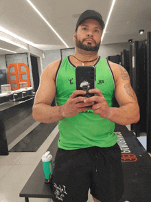a man in a green tank top is taking a selfie in a gym