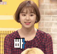 a woman wearing a plaid shirt has a sticker on her chest that says ' ba '