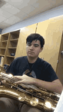 a young man is playing a saxophone in a room .