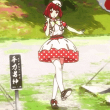 a girl in a red and white polka dot dress is standing in front of a sign that says ' a '