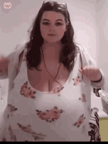 a woman with very large breasts is wearing a floral dress and a white sweater .