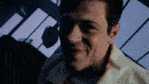 a close up of a man 's face with a blurred background . he is smiling and looking at the camera .