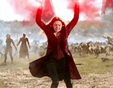 a woman in a red coat is standing in a field with her arms up in the air .