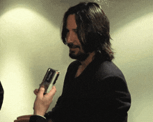a man with long hair and a beard holds a cell phone in his hand