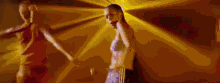 two women are dancing in a dark room with a yellow background .