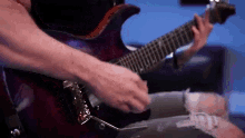 a man is playing a purple electric guitar in a dark room .
