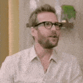 a man wearing glasses and a white shirt is making a funny face .