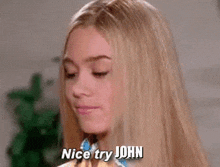 a woman with long blonde hair is looking at the camera and says nice try john .