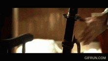 a close up of a person holding a sword with gifrun.com written below it