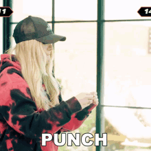 a woman wearing a hat and a tie dye hoodie says punch in white letters
