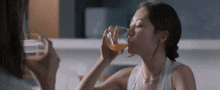 a woman drinking a glass of orange juice from a glass