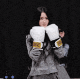 a girl wearing everlast boxing gloves stands in front of a black curtain