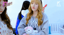 a girl holding a stuffed animal wearing a sweater that says ixn on it