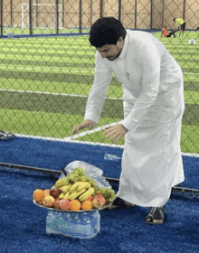 a man in a white robe is holding a plate of fruit