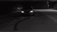 a car is driving down a dark road at night .