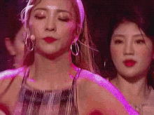 two women are standing next to each other on a stage in front of a crowd .