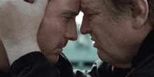 two men are touching their foreheads with their hands and looking at each other