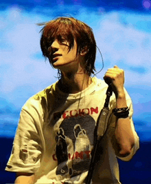 a man singing into a microphone wearing a shirt that says " colon "